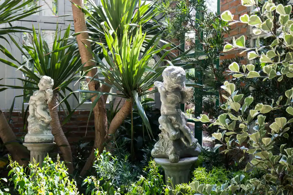 deux sculptures d'angelots dans un jardin d'hiver luxuriant