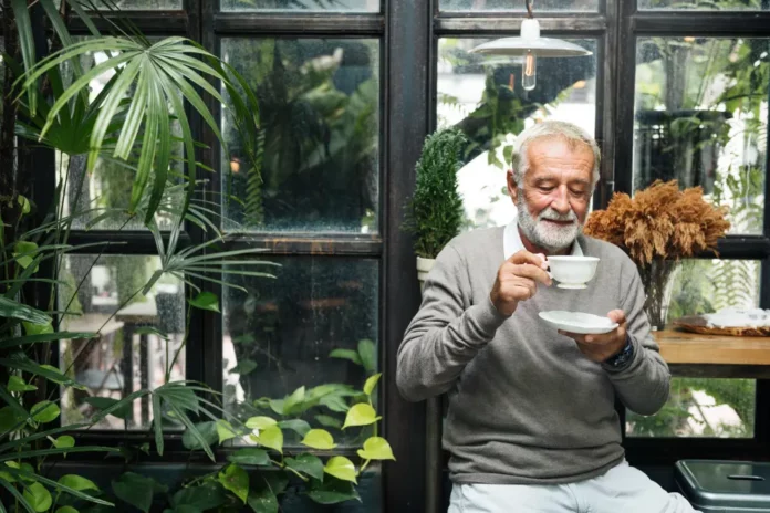 homme prenant un café dans sa véranda entouré de plantes