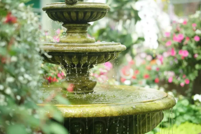 Photo fontaine qui coule de l'eau décorant le jardin fleuri