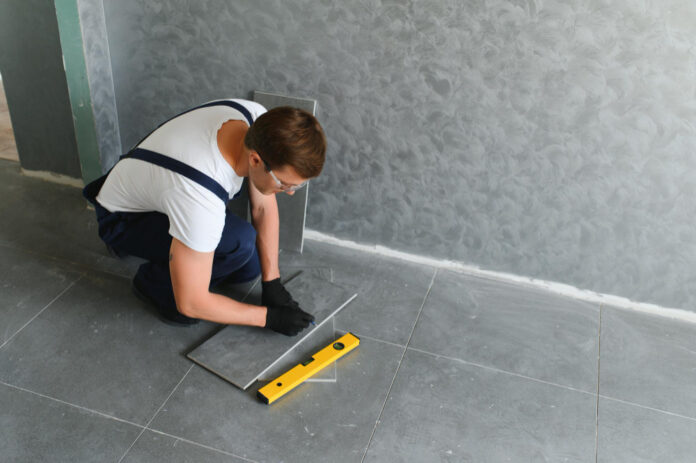 homme qui pose du carrelage anti-dérapant gris